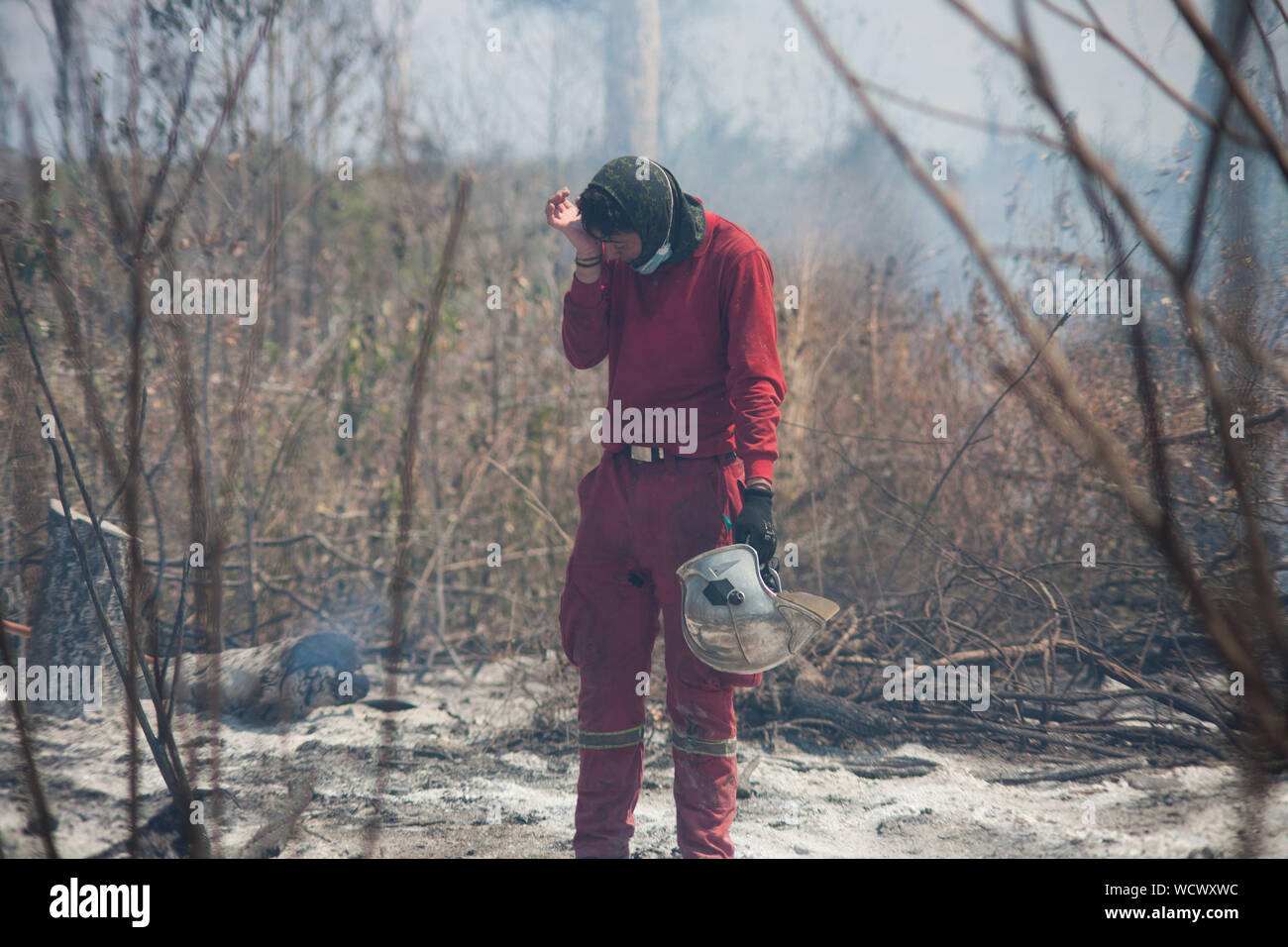 Santa Rosa De Tucabaca, Bolivien. 28 Aug, 2019. Ein Mitglied der Feuerwehr Wischtücher sein Gesicht auf eine Mission zu einem verbrannten Feld. Den Einsatzkräften im Osten Boliviens weiterhin die verheerenden Waldbrände zu enthalten. 1800 Soldaten und 450 Polizisten sind in der löscharbeiten in der Chiquitania Region einbezogen zu werden. Angesichts der verheerenden Waldbrände im Amazonasgebiet, die Staats- und Regierungschefs der Region wollen auf, eine gemeinsame Strategie auszuarbeiten. Die Präsidenten der Amazon Länder wird am 6. September in der kolumbianischen Stadt Leticia erfüllen. Credit: Gaston Brito/dpa/Alamy leben Nachrichten Stockfoto