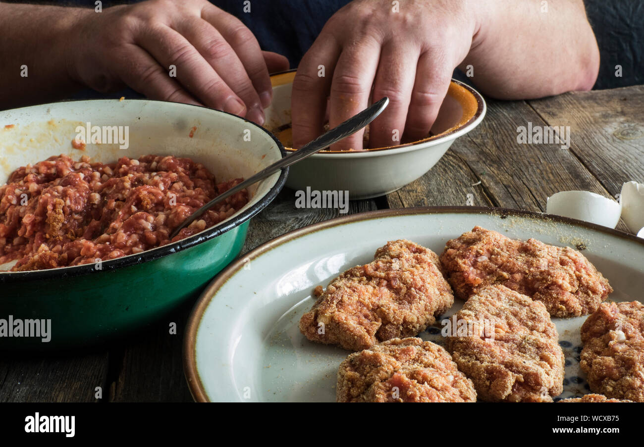 Zugeschnittenes Bild von Händen Teig Mischen von Hackfleisch am Tisch Stockfoto