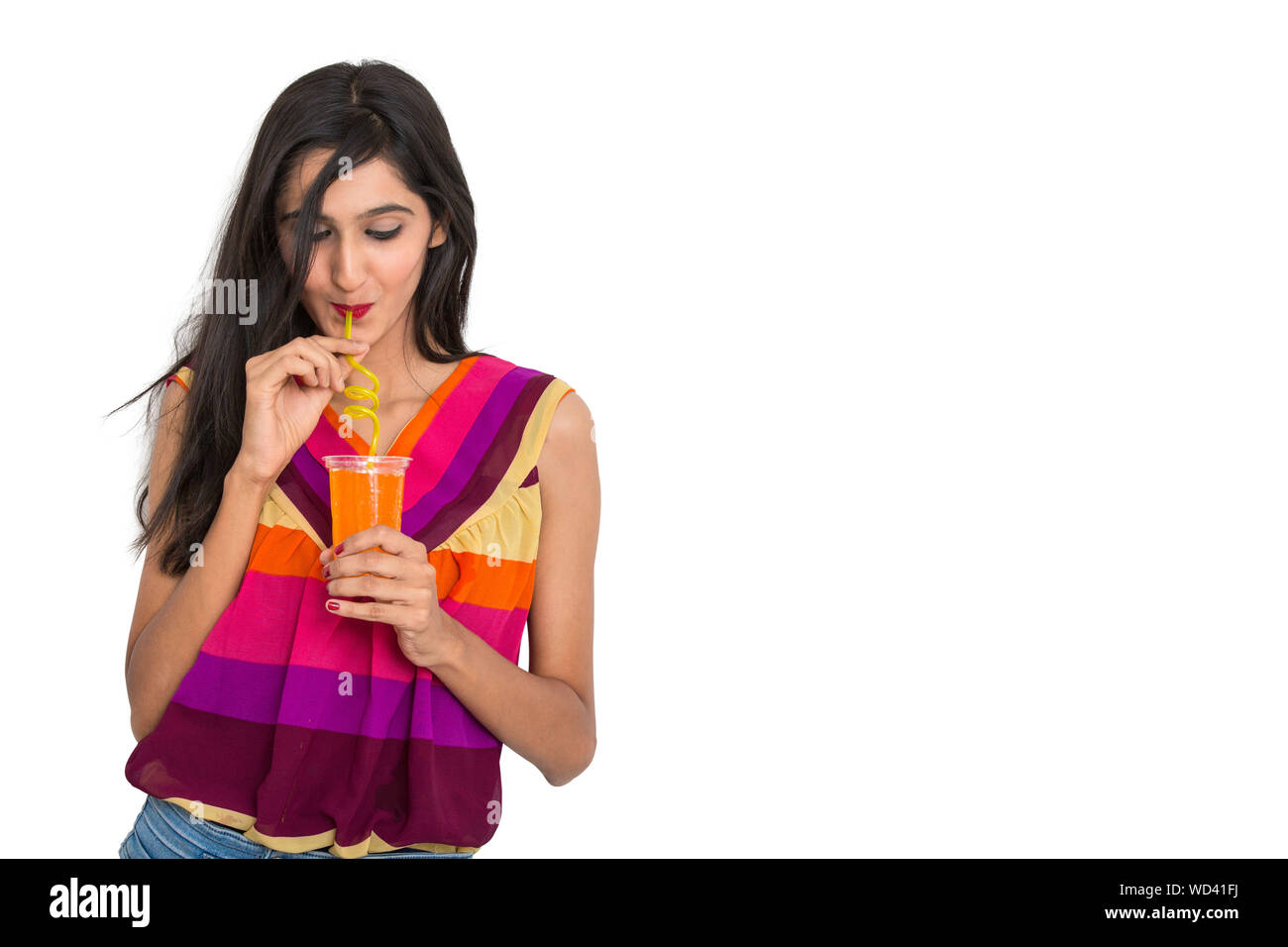 Indisches Mädchen trinken orange Soft drink auf isoliert weißer Hintergrund Stockfoto