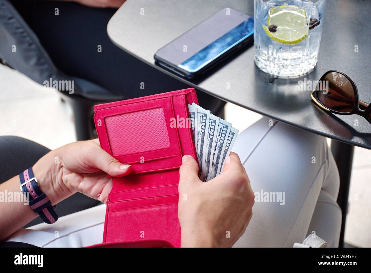 Mittelteil der jungen Frau Zahlung Rechnung im Restaurant. Rote Geldbörse mit Dollar Stockfoto