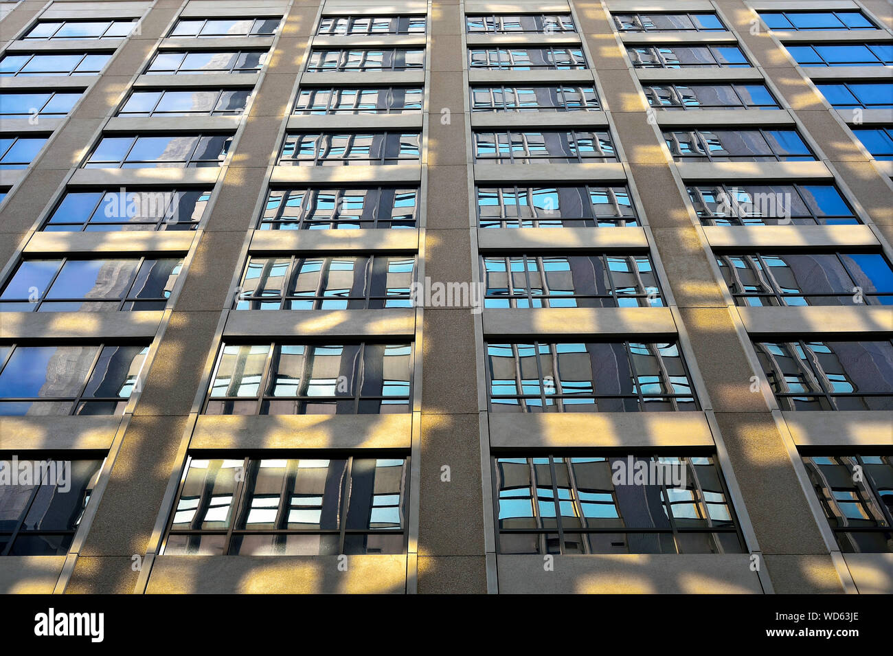Perspektivische Ansicht des modernen Fassade des Bürogebäudes mit geometrischen Mustern in Beton und Glas mit Abendsonne und blauen Tönen Stockfoto