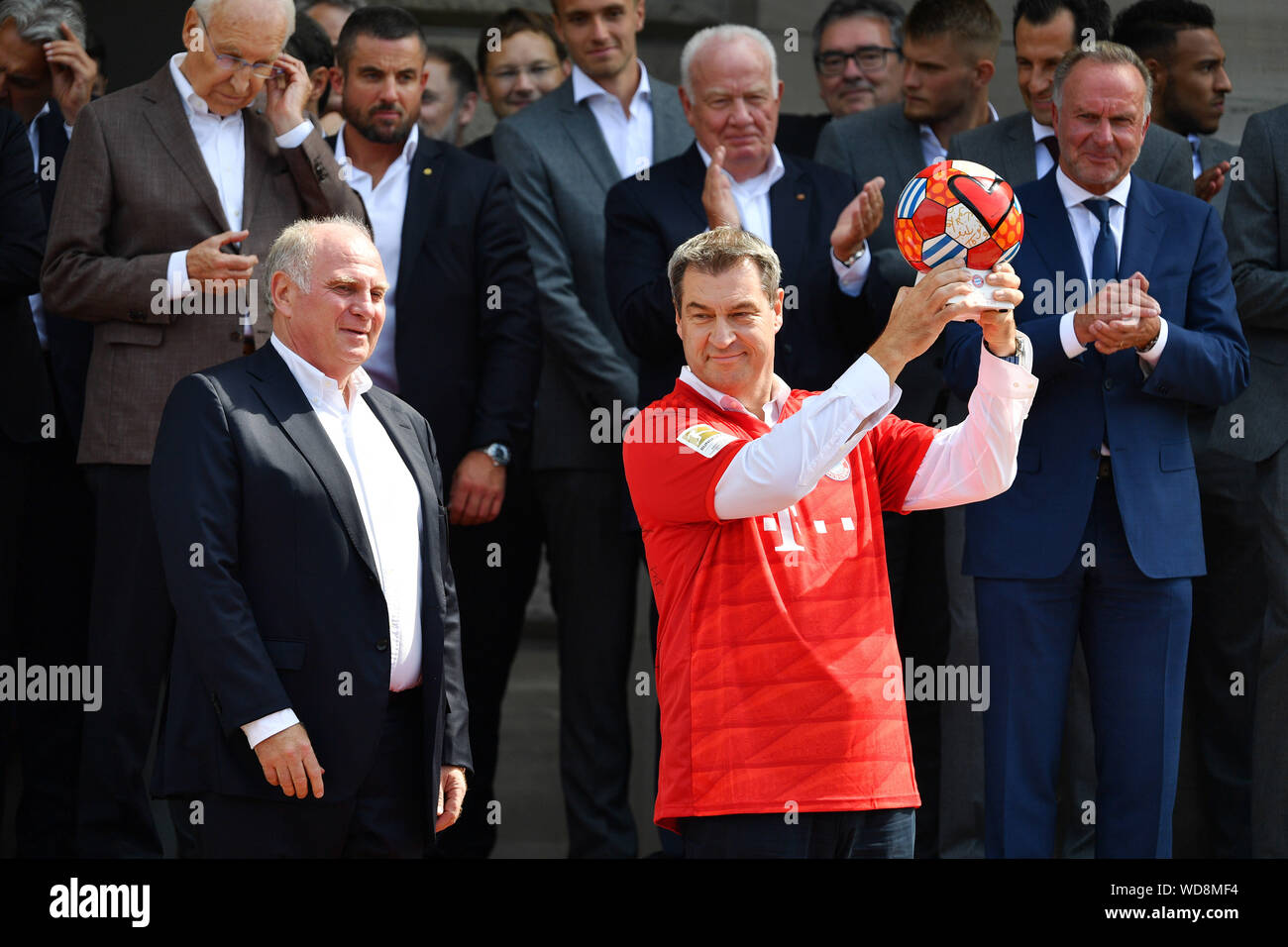 Uli Hoeneß (Honess, Präsident des FC Bayern München), stellt Markus Soeder  (Der bayrische Ministerpraesident und CSU-Vorsitzende) mit einem Trikot mit  der Nummer 12 und eine Kugel. Rezeption Der bayerische Ministerpraesident  zu Ehren
