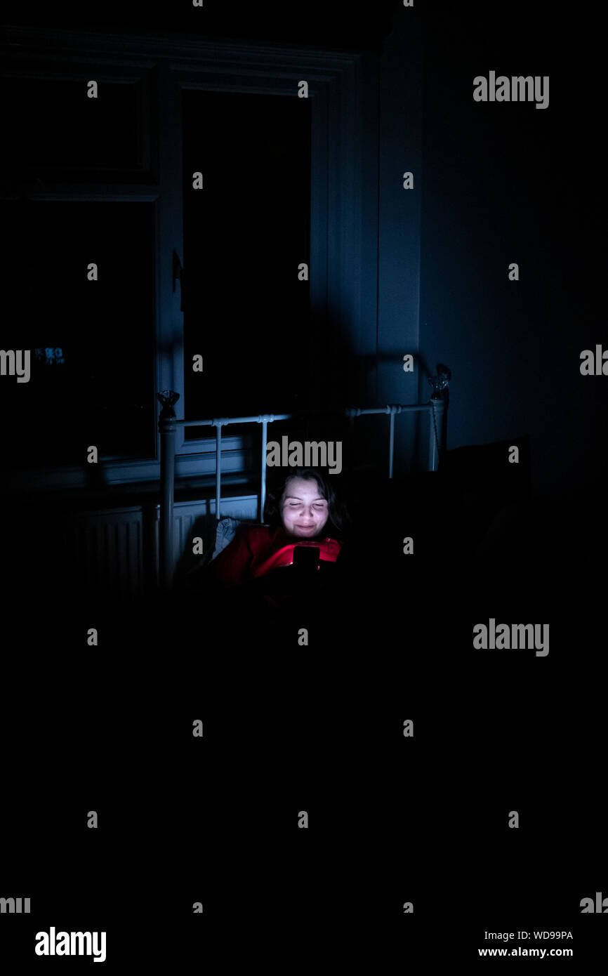 Junges Mädchen plaudern auf Ihr Telefon spät in der Nacht, Stockfoto