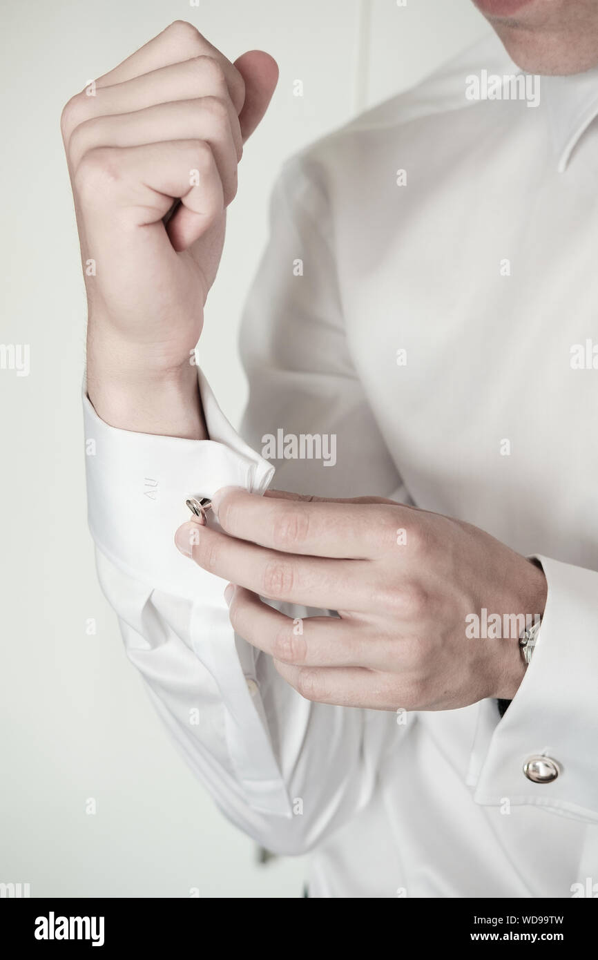 Junger Mann Manschettenknöpfe zur Festsetzung auf weißem formale Shirt - close-up Detail Stockfoto