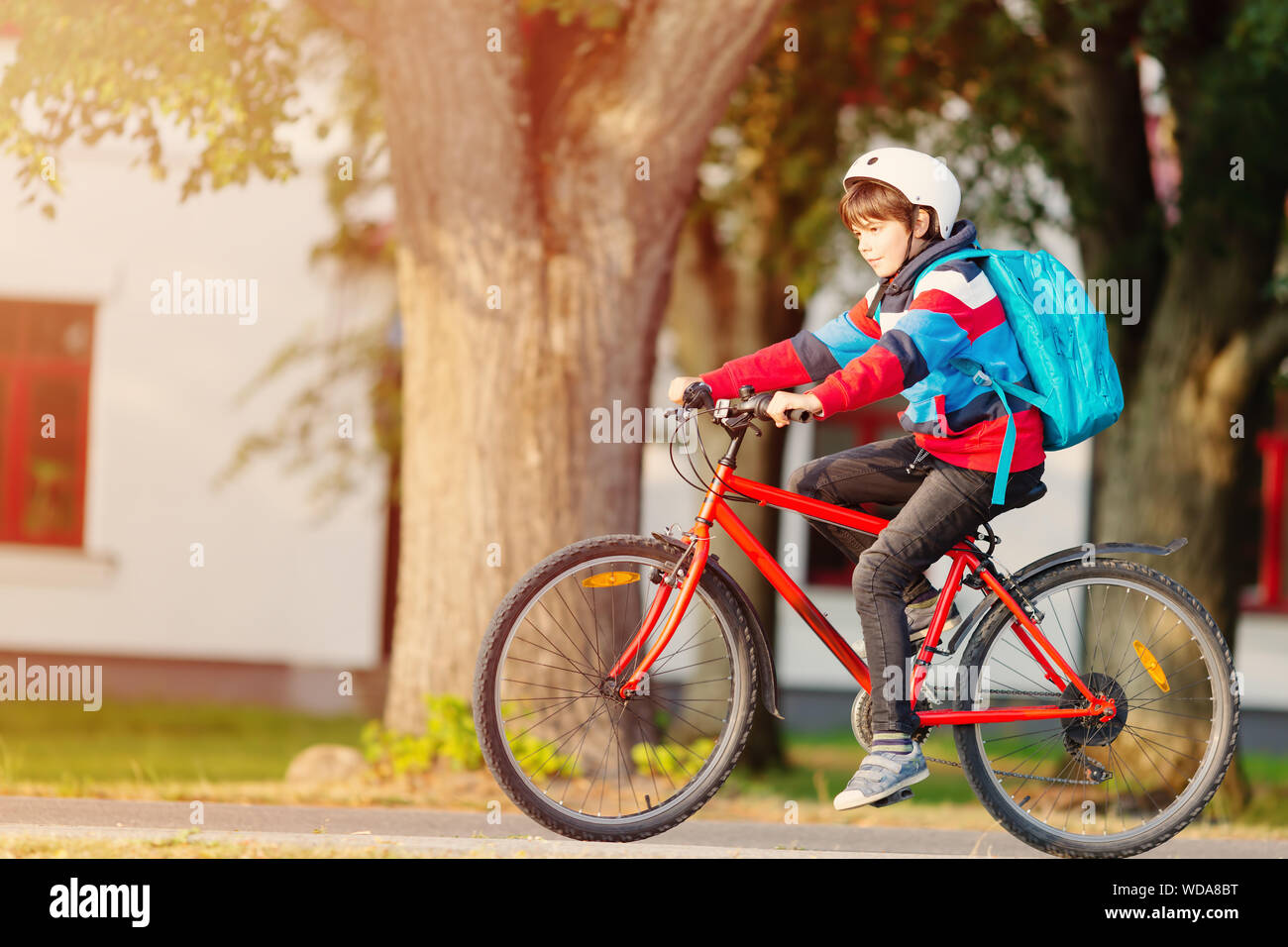 Kind mit Rucksack, auf dem Fahrrad im Park in der Nähe der Schule Stockfoto