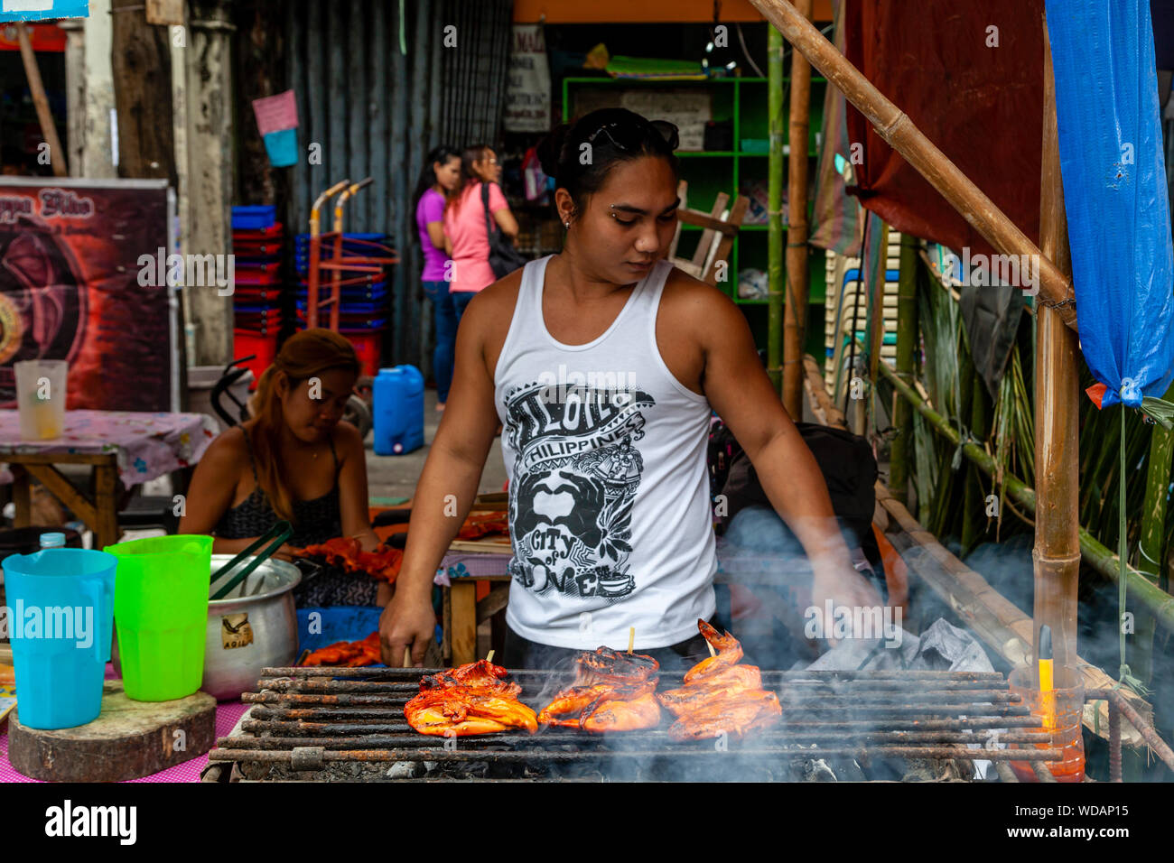 Eine junge Filipino Mann Kochen Fleisch auf dem Grill, Iloilo City, Panay Island, Philippinen Stockfoto