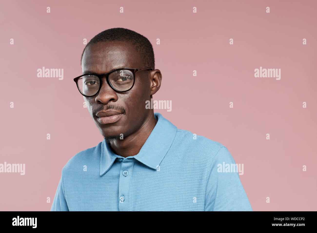 Portrait der Afrikanischen hübscher Kerl in Brillen und in Freizeitkleidung auf Kamera über rosa Hintergrund Stockfoto