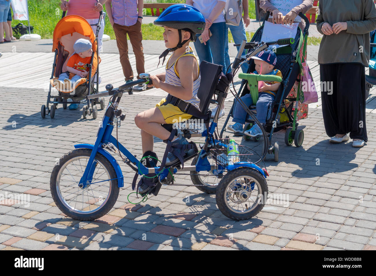 Russland, Kazan - 31. Mai 2019: behinderten Jungen in Gläsern auf einem Dreirad auf einem hellen, sonnigen Tag. Charity Radtour. Der Eintritt ist frei. Stockfoto