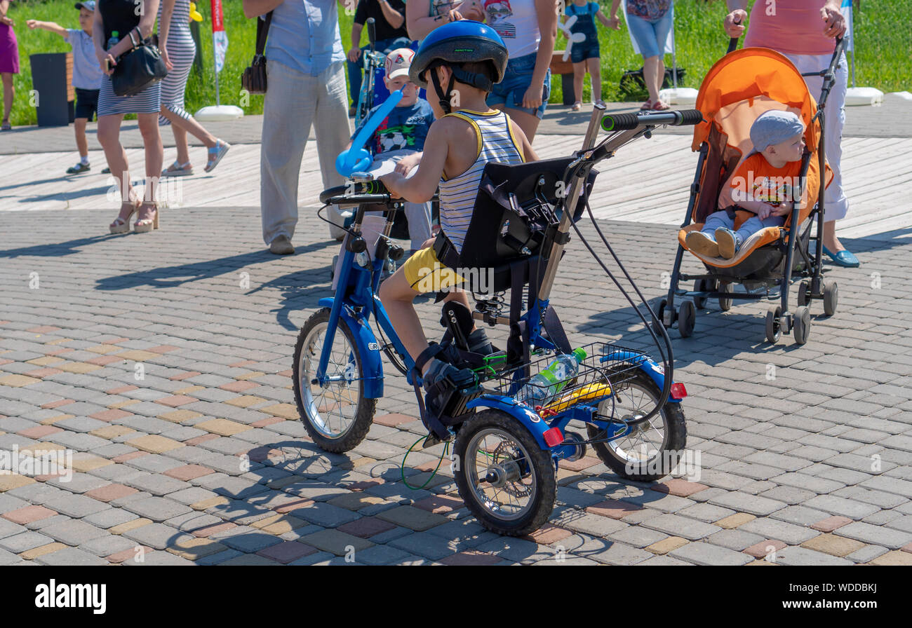 Russland, Kazan - 31. Mai 2019: behinderten Jungen in Gläsern auf einem Dreirad auf einem hellen, sonnigen Tag. Charity Radtour. Der Eintritt ist frei. Stockfoto