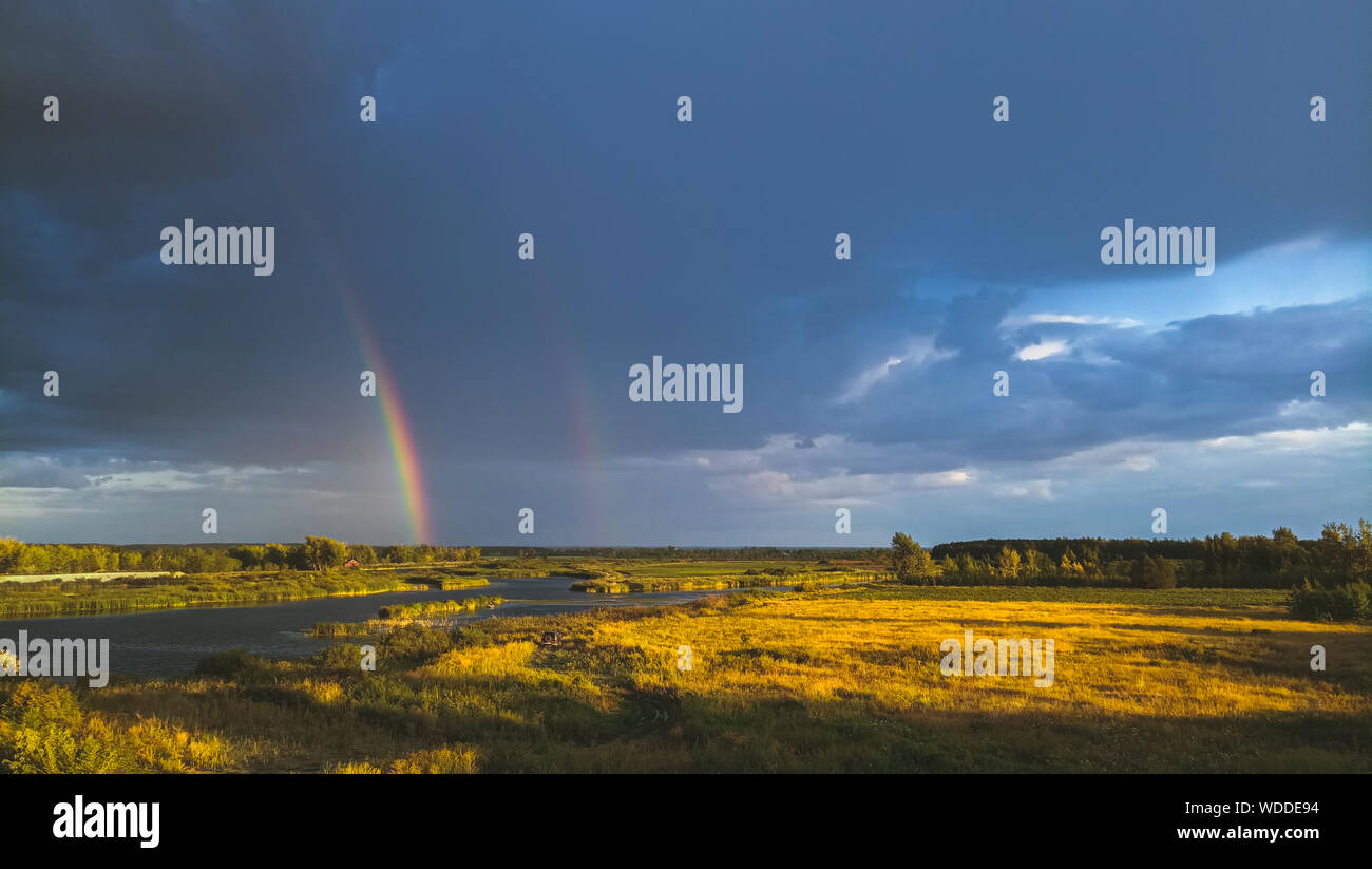 Regenbogen nach dem regen auf dem Hintergrund der Gewitterwolken. Stockfoto