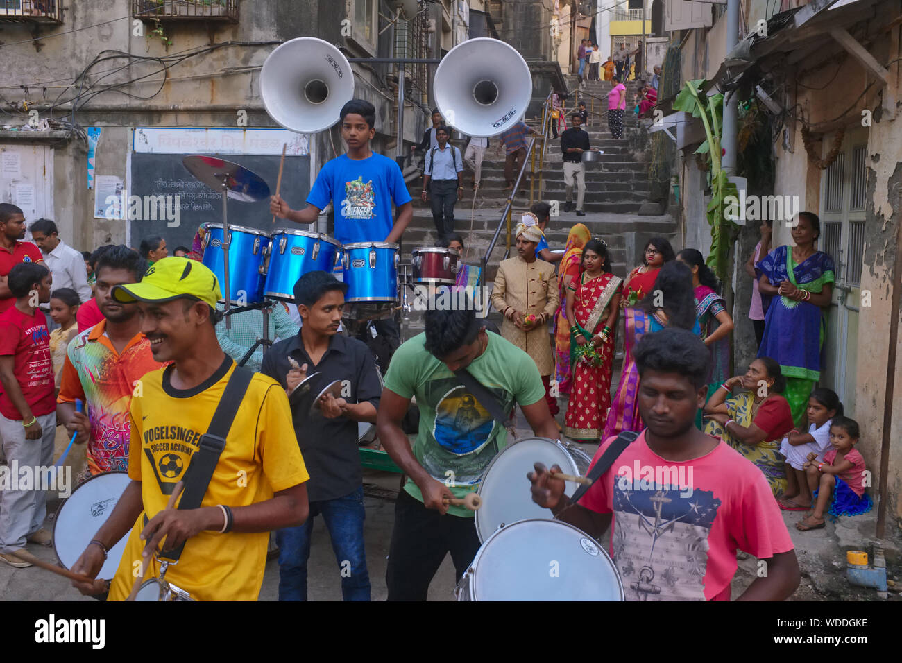 Während einer unauffälligen indischen Hochzeit spielt eine Amateur-Hochzeitsband in einem Hinterhof in Mumbai, Indien, mit dem Paar und seinen Freunden im Hintergrund Stockfoto