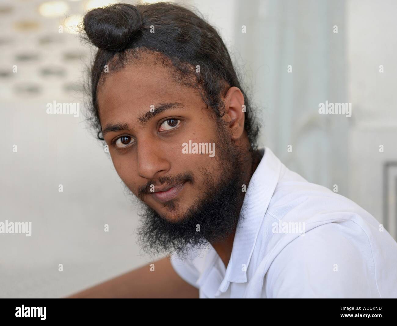 Junge indische Sikh devotee schaut in die Kamera, bevor er seine traditionelle Sikh Turban (Dastar). Stockfoto