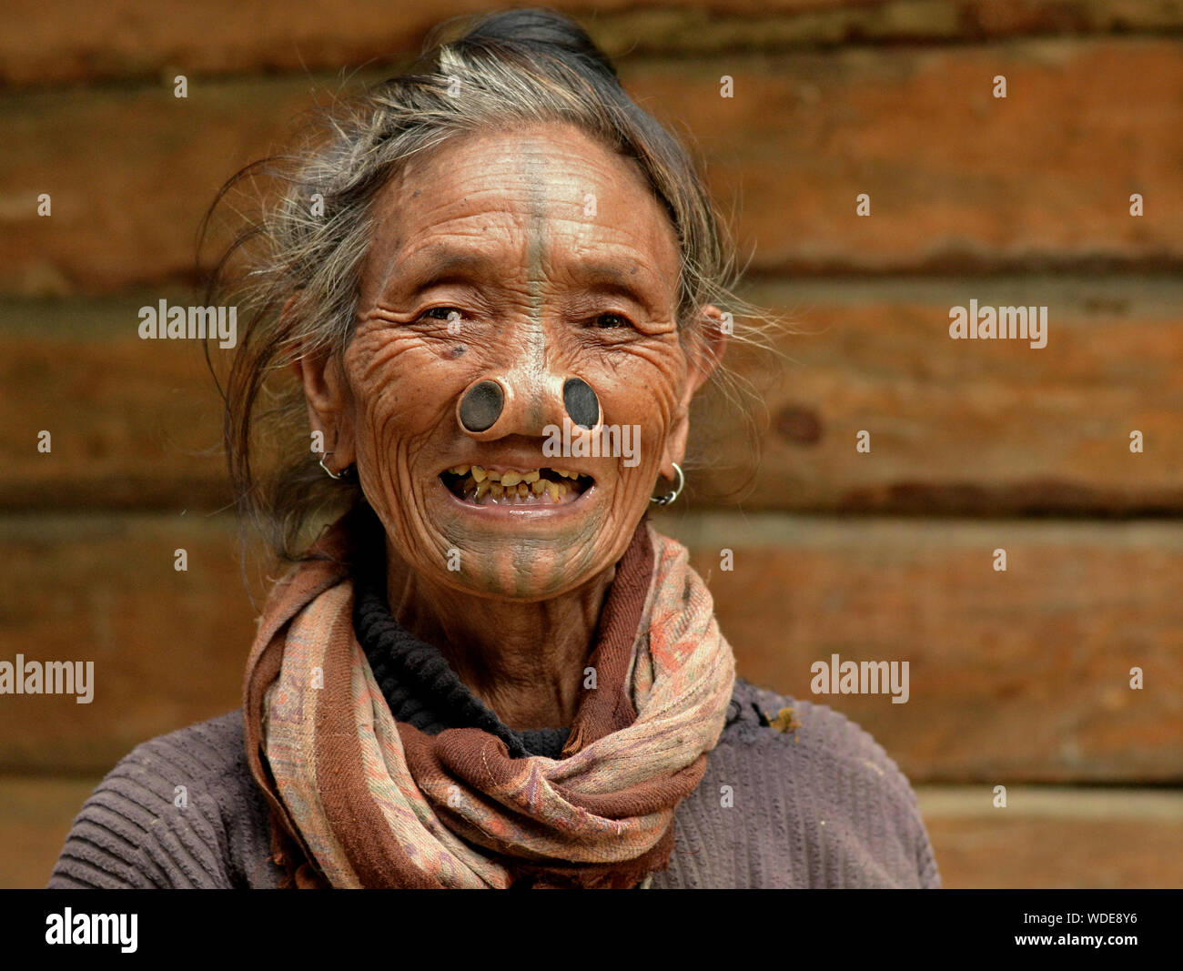 Alte indische Apatani tribal Frau mit schwarzem Holz- nase Stopfen (yawping hullo) und unverwechselbares Gesicht Tribal Tattoo posiert für die Kamera. Stockfoto