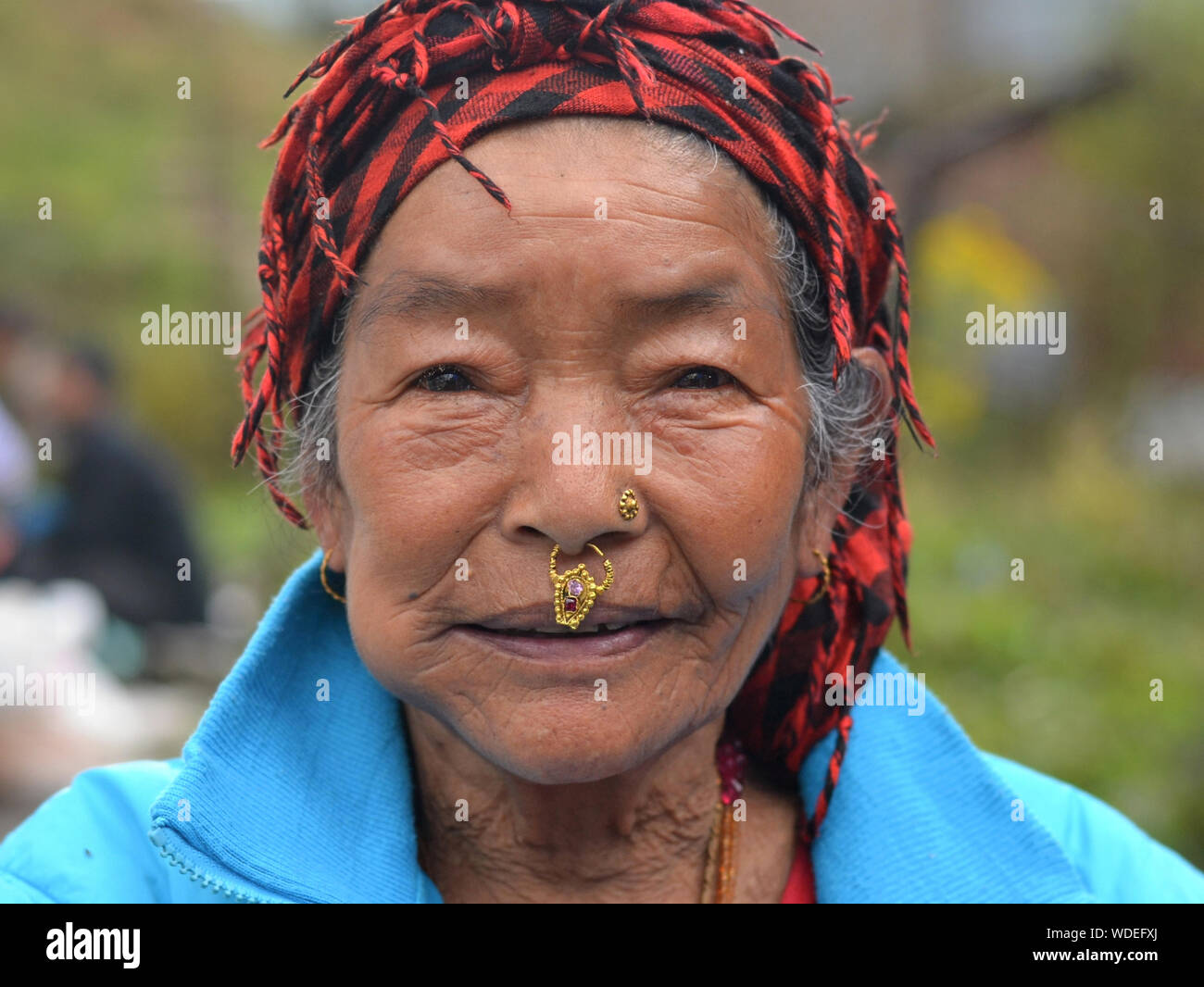 Ältere Nepali Rai Frau mit gebrochenen Nase Tribal Schmuck posiert für die Kamera. Stockfoto