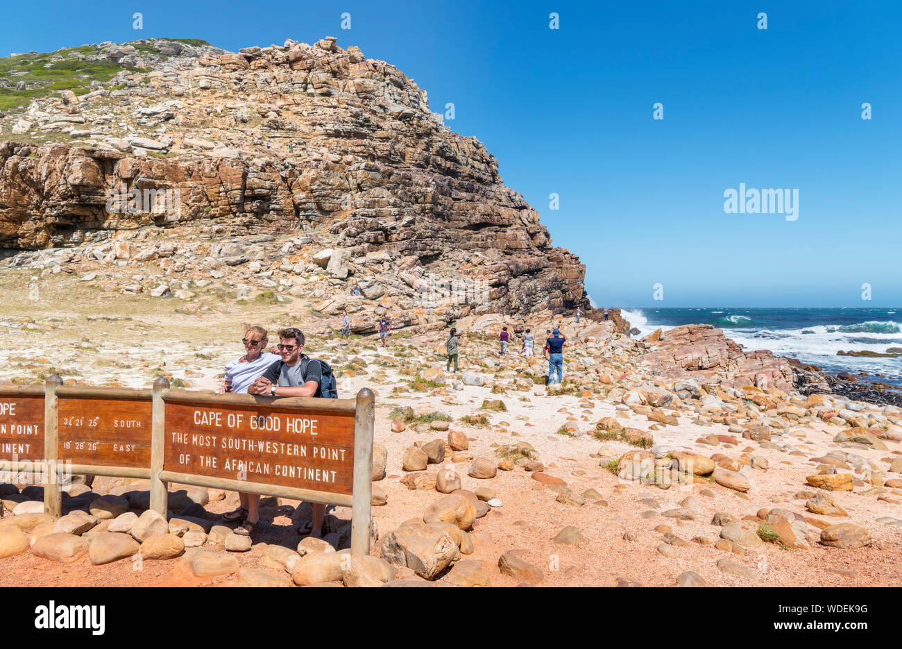 Paar für ein Foto von dem Schild am Kap der Guten Hoffnung, die am südwestlichen Punkt auf dem afrikanischen Kontinent, Western Cape, Südafrika posing Stockfoto