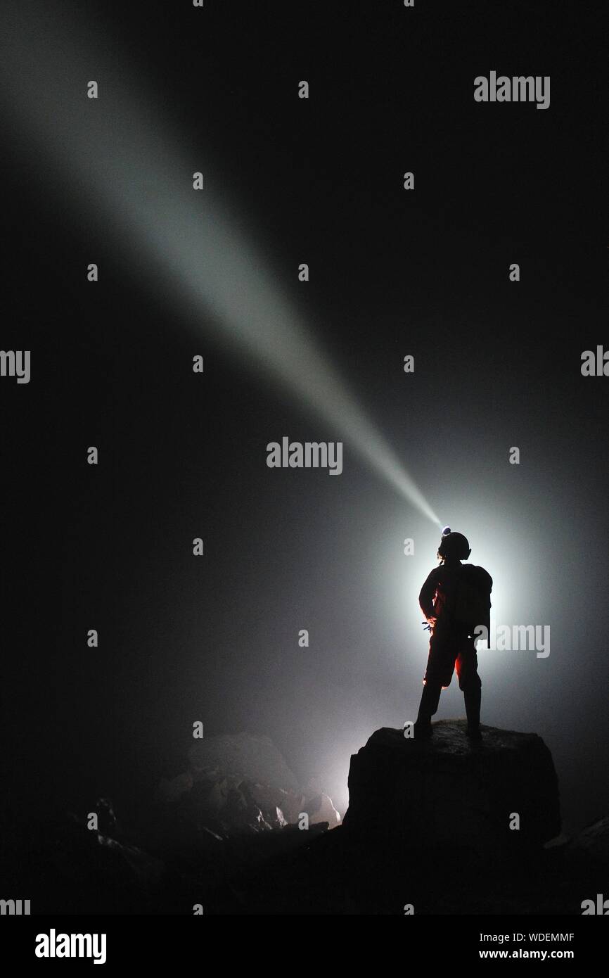 Mann mit Taschenlampe beim Stehen auf Rock bei Nacht Stockfotografie - Alamy