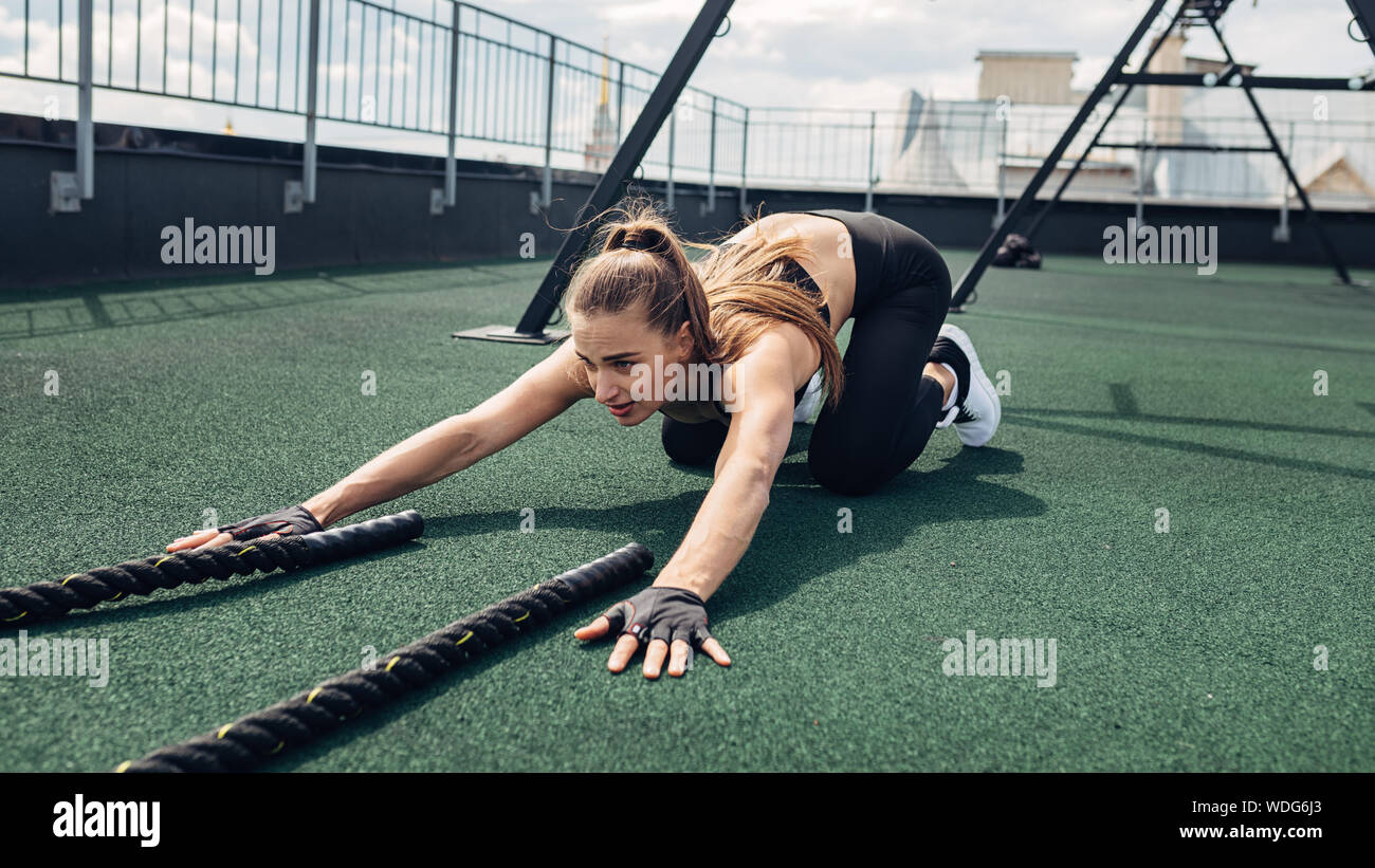 Erschöpft fitness liegende Frau auf dem Dach nach intensivem Training mit Schlacht Seile Stockfoto