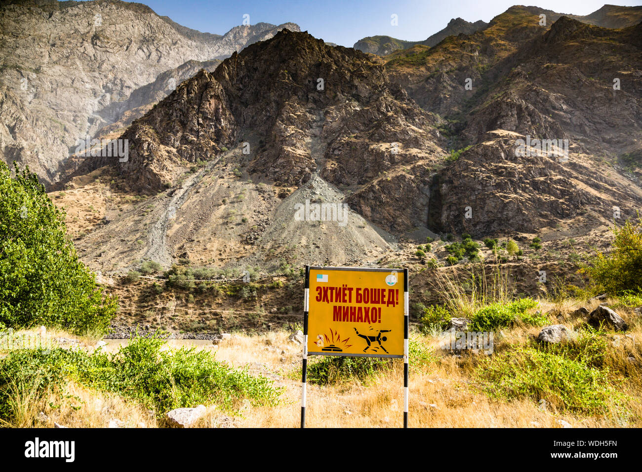 Ein Landminen-Warnschild steht direkt neben der Pamir-Autobahn nahe Dashti-Jum, Tadschikistan, wo vermintes Gelände noch entlang der Grenze zu Afghanistan liegt. Stockfoto