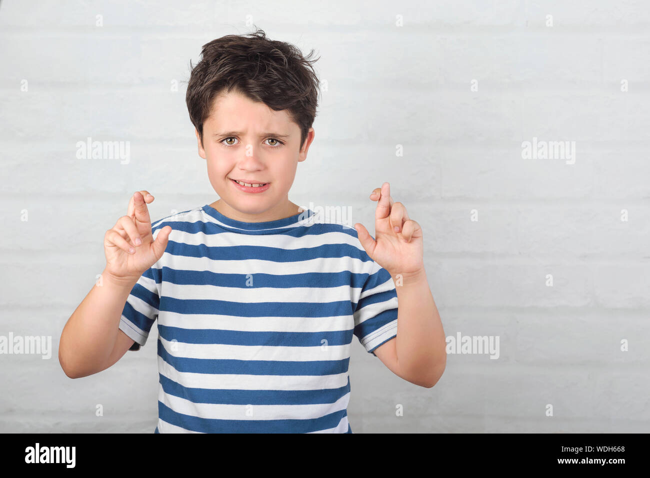 Kind überschreiten ihre Finger hofft für Gud Glück auf backstein Hintergrund Stockfoto