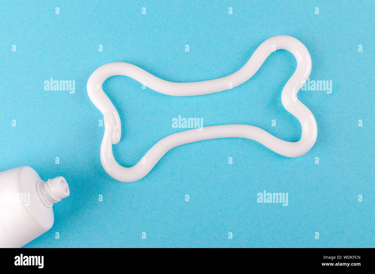 Ein Knochen von weiße Zahnpasta, Tier Zähne Pflegekonzept, auf blauem Hintergrund Stockfoto