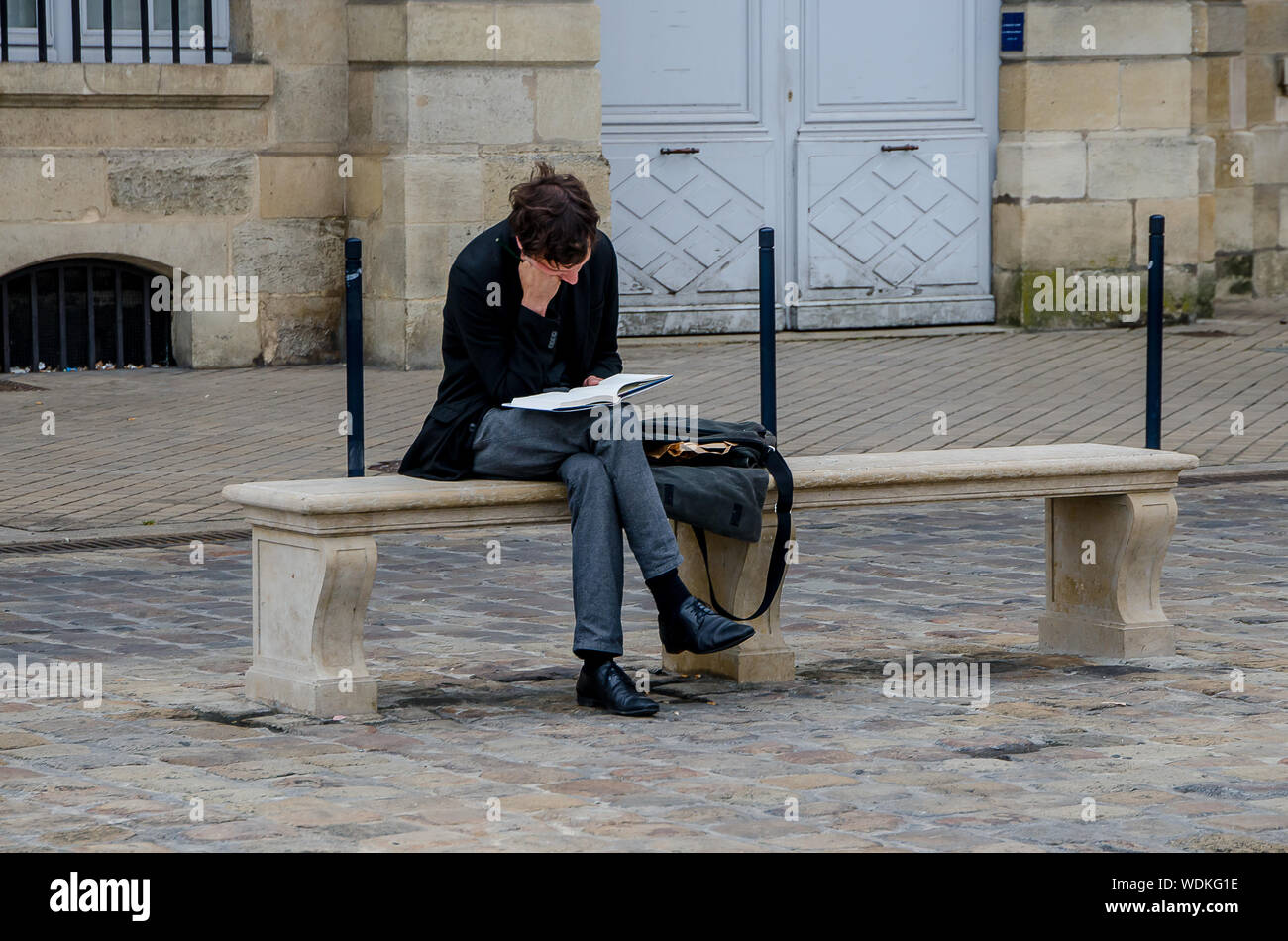 Mann lesen sitzen auf einer Bank in Bordeaux, Frankreich, im September 2013 Stockfoto