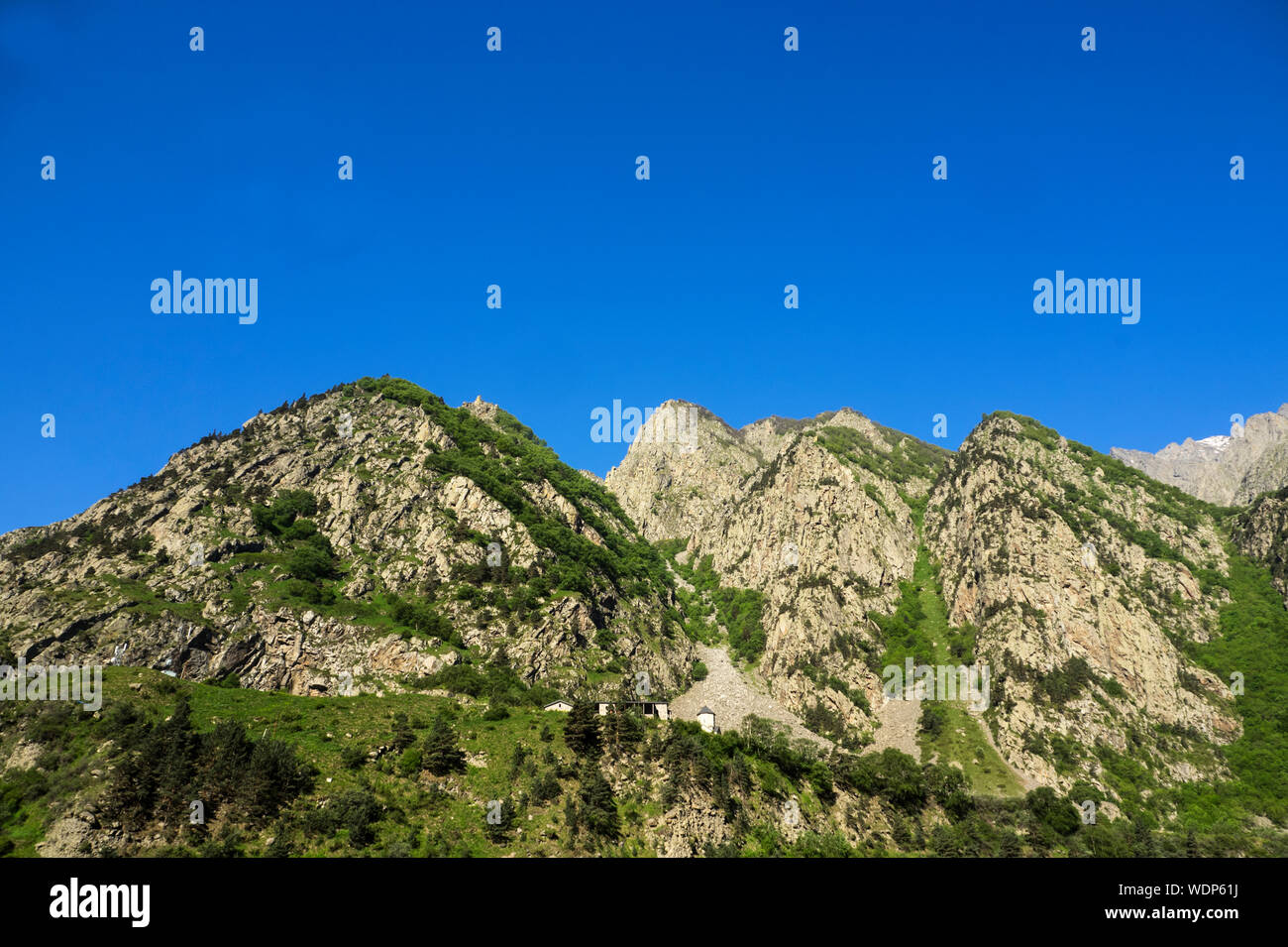 Idyllische Schoß der Berge gegen den klaren blauen Himmel bei Stepantsminda Stockfoto