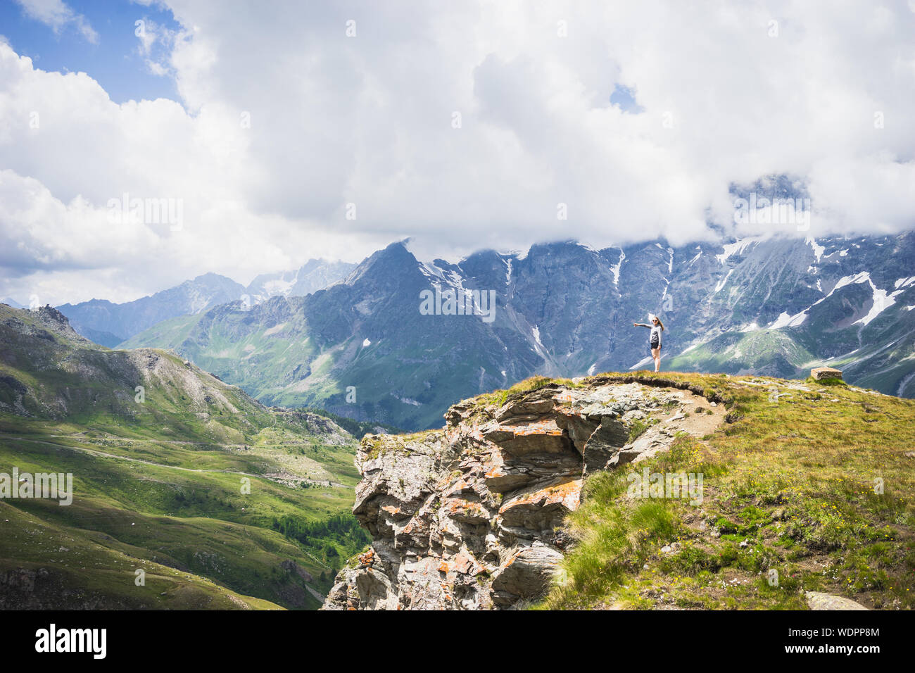 Fernsicht auf Frau steht auf Grass gegen Berge und Himmel Stockfoto