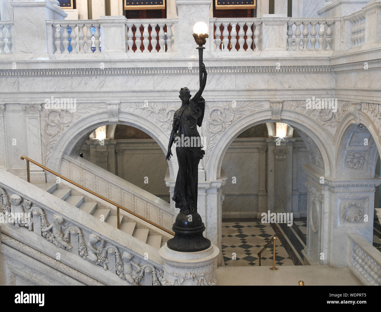 Große Halle. Blick auf die große Treppe und Bronze Statue der weiblichen Figur auf newel post Holding eine Fackel der elektrisches Licht. Bibliothek des Kongresses Thomas Jefferson, Washington, D.C. Stockfoto