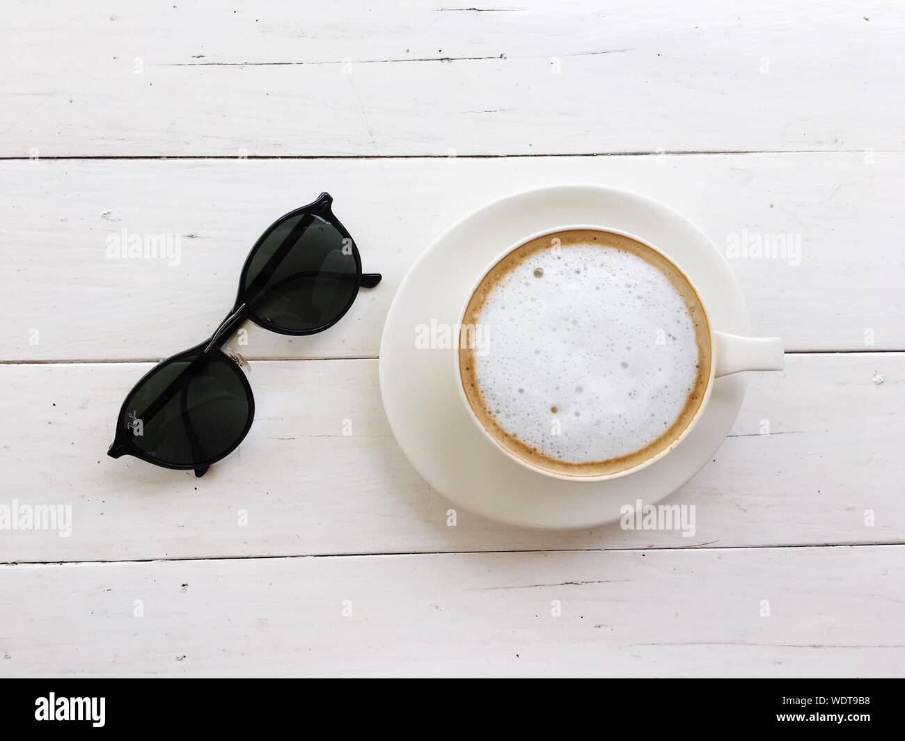 Direkt über Schuss von Kaffee mit Sonnenbrille auf Tisch Stockfoto