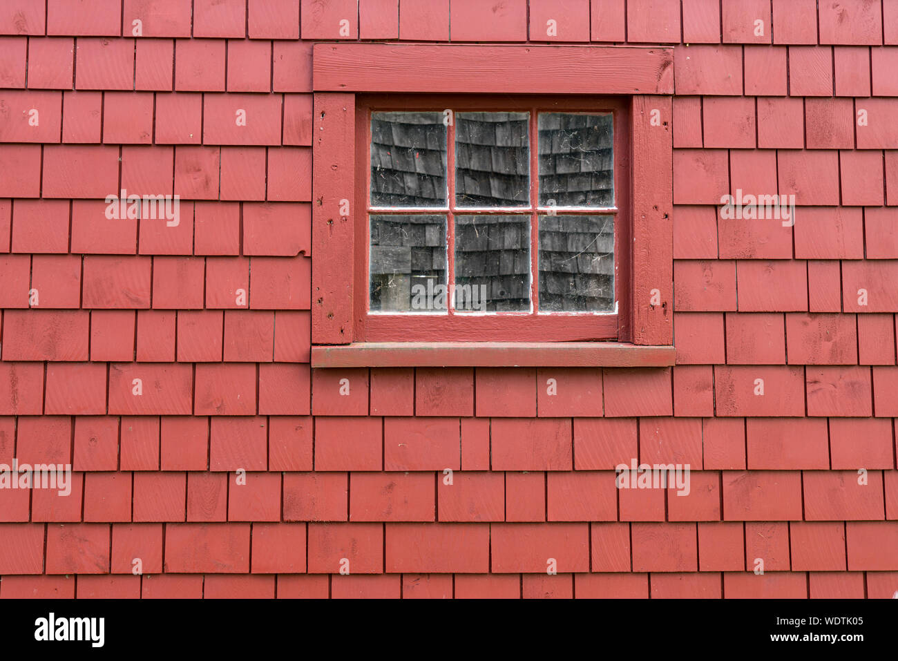 Kleine alte Holz- Fenster auf das Äußere eines roten Kies Wand Stockfoto