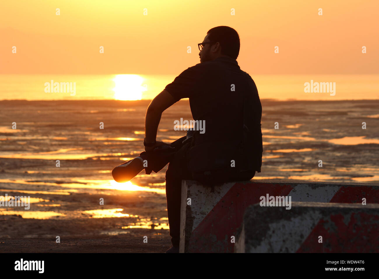 Silhouette Mann Sitzt Am Strand Bei Sonnenuntergang Stockfotografie Alamy