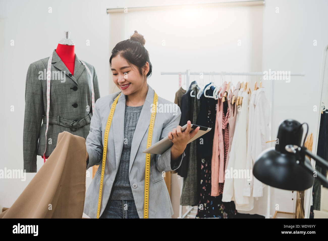 Fashion Designer Stylist in Geschäft Inhaber Workshop mit Tablet und Kunden Kontakt Liste. Maßgeschneiderte und Konzept nähen. Portrait von happy and Trendy fas Stockfoto