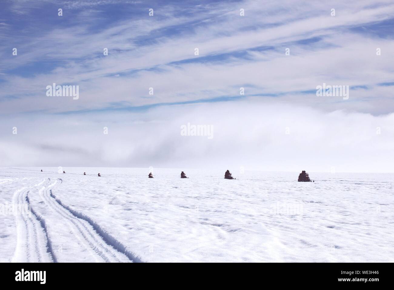 Menschen mit dem Schneemobil auf Schnee mit der Vatnajökull gegen Sky Stockfoto