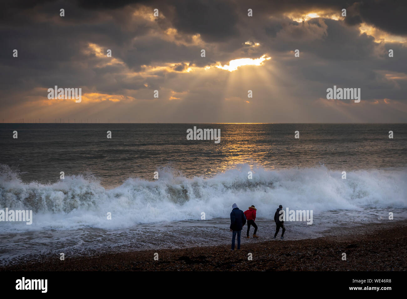 3 Männer an Brighton Beach die Sonne untergeht Stockfoto