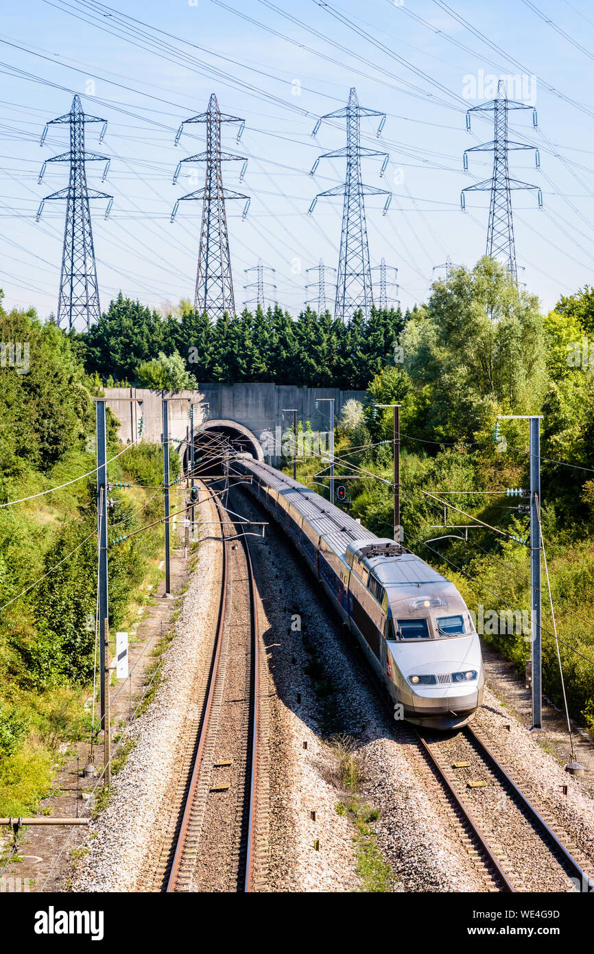 Ein TGV-Zug im Atlantischen Livree kommt aus einen Tunnel unter einer Reihe von Sendemasten auf der LGV Atlantique high-Speed Railway. Stockfoto