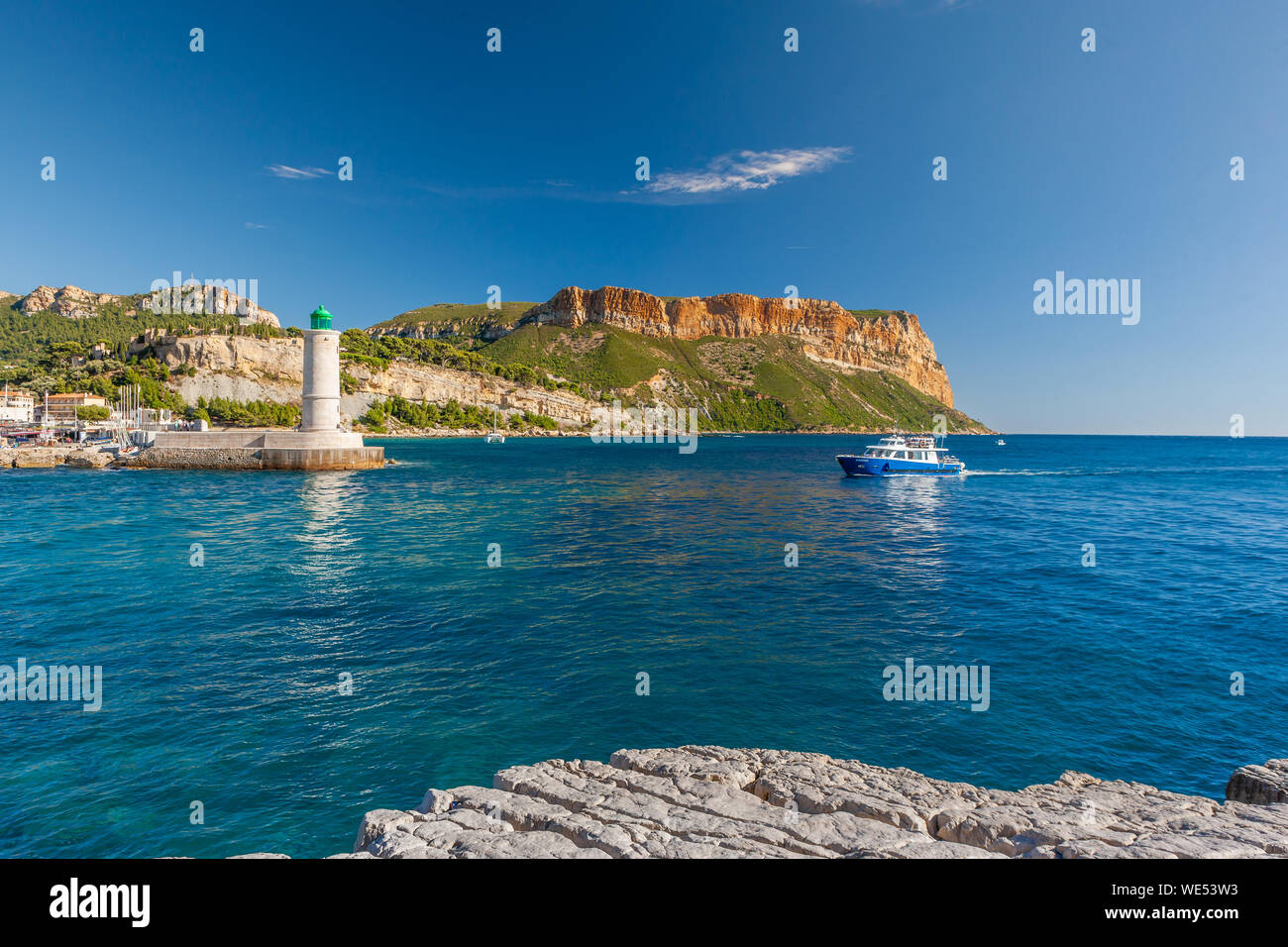 Stehend auf dem felsigen Ufer mit Blick auf ein kleines Boot in den Hafen von Cassis. Stockfoto