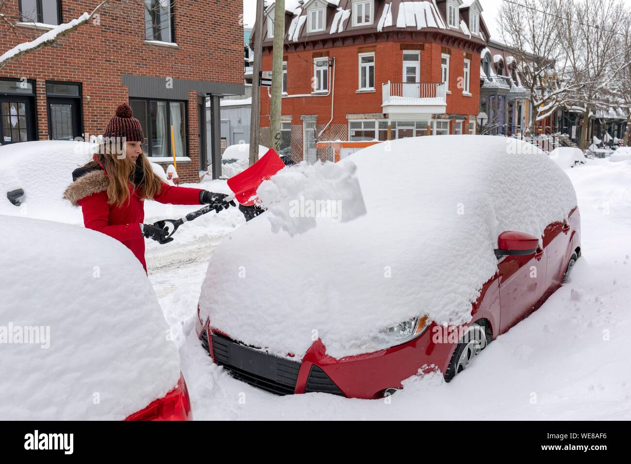 Kanada, in der Provinz Quebec, Montreal, die Plateau-Mont-Royal Nachbarschaft nach einem Schneesturm, eine Frau Schnee schaufeln Ihr Auto Stockfoto