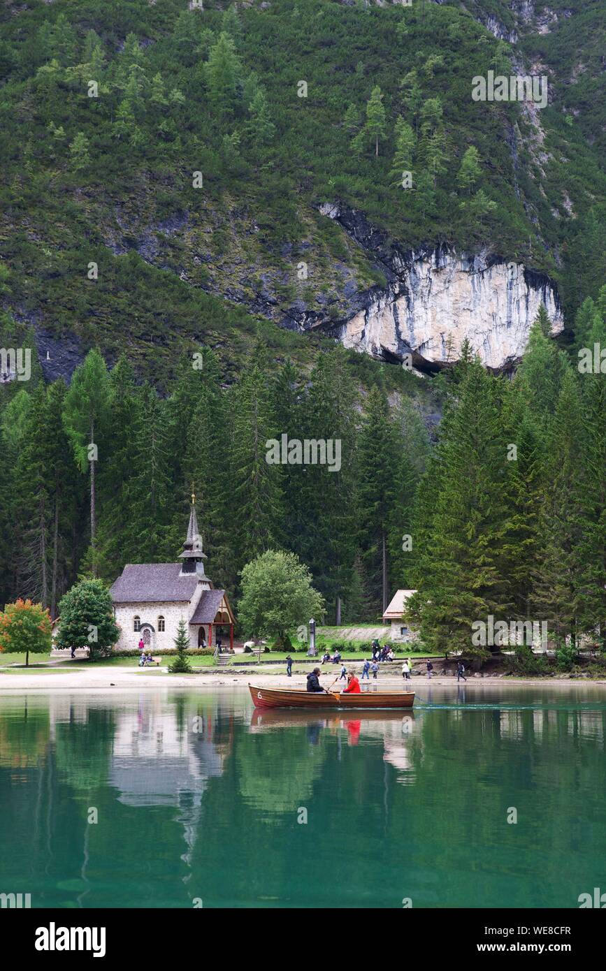 Italien, Autonome Provinz Bozen, Hochpustertal, See Pragser Tal, Ruderer in einem Boot auf dem smaragdgrünen Wasser des Sees mit einer Kirche auf der Bank und einem grünen Berg für die Dekoration Stockfoto