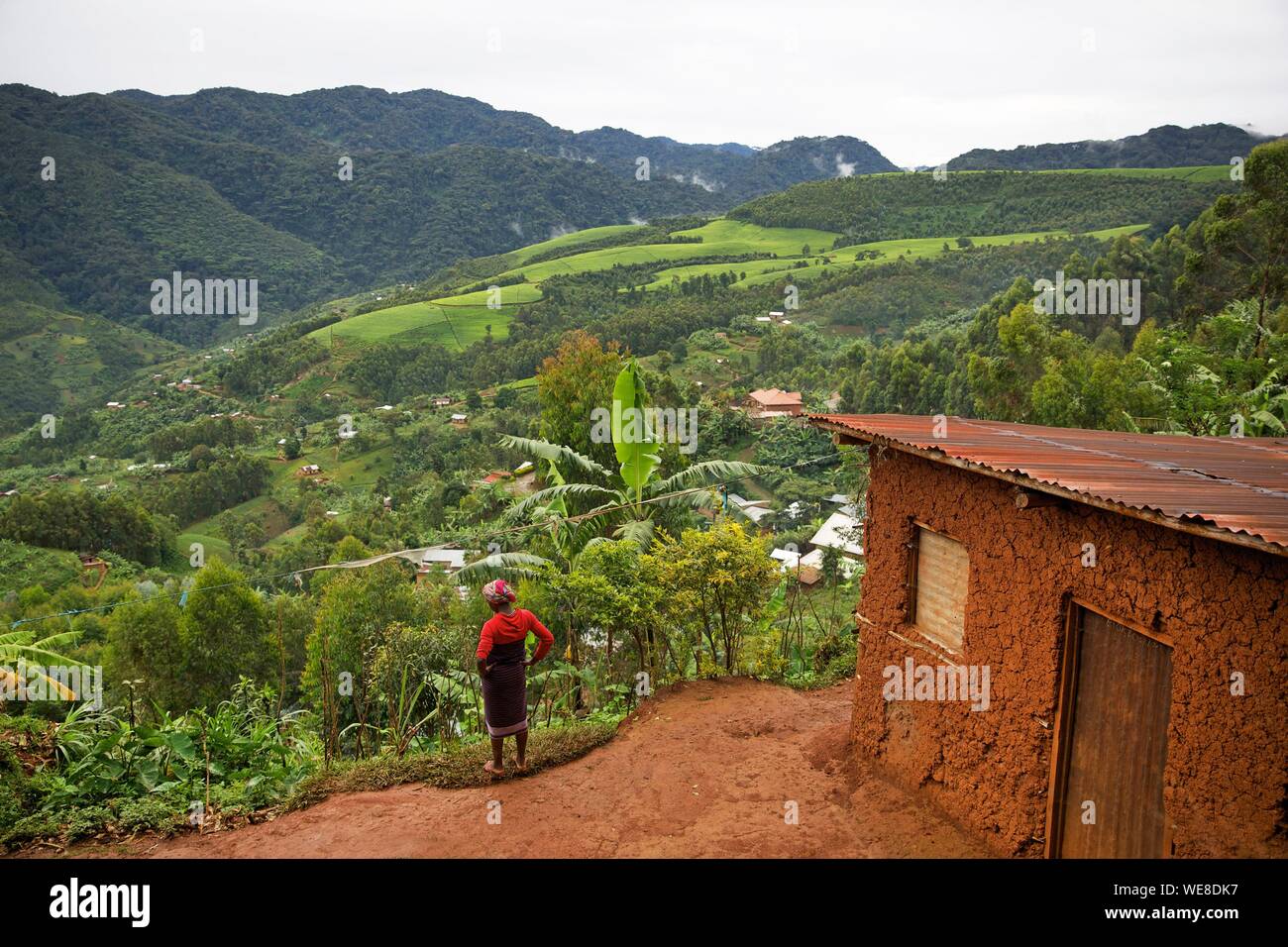 Ruanda, Nyungwe, Frau vor ihr Lehmhaus mit Blick auf die grünen Hügel des Nyungwe National Park Stockfoto