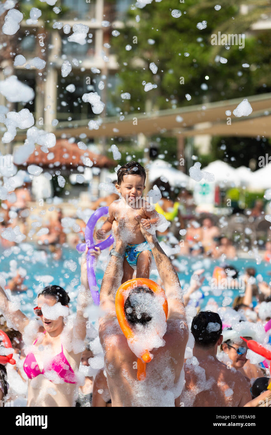 Ein Kind ist aloft in einem Schaum Party in einen Pool im Urlaub statt Stockfoto