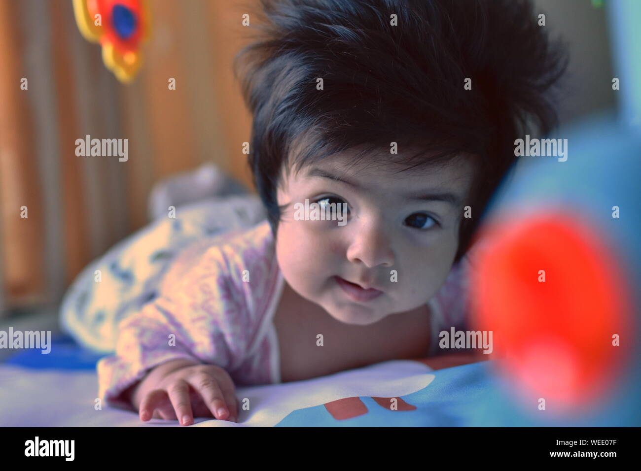 Süße Mischlinge baby girl elegant in die Kamera schaut unter ihrem Spielzeug im Kindergarten Stockfoto