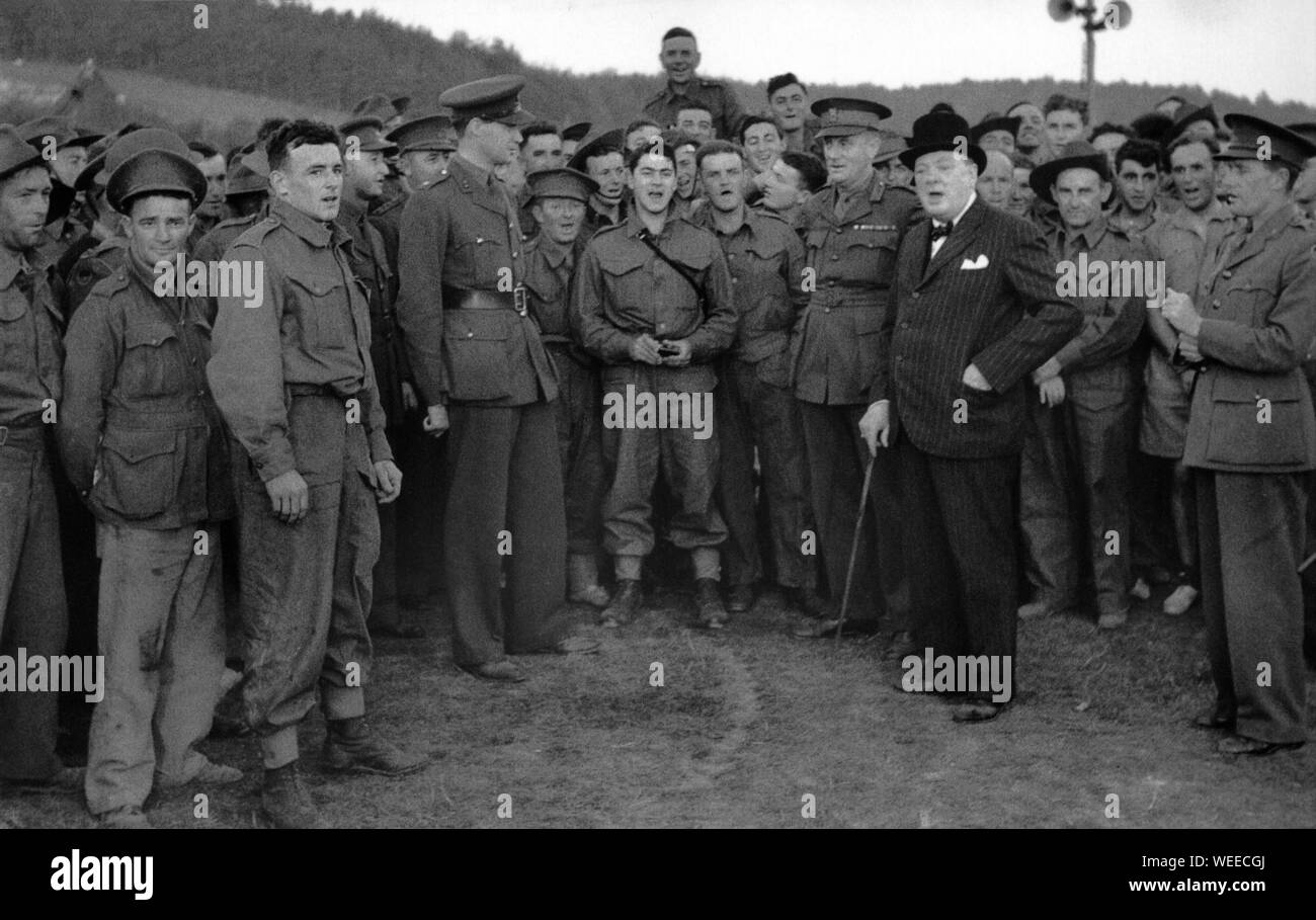Churchill begleitet den Gesang bei einem Besuch in einem australischen Militärlager. Duncan Sandys in Offiziersuniform auf der linken Seite der Fotografie.9. September 1940 Stockfoto