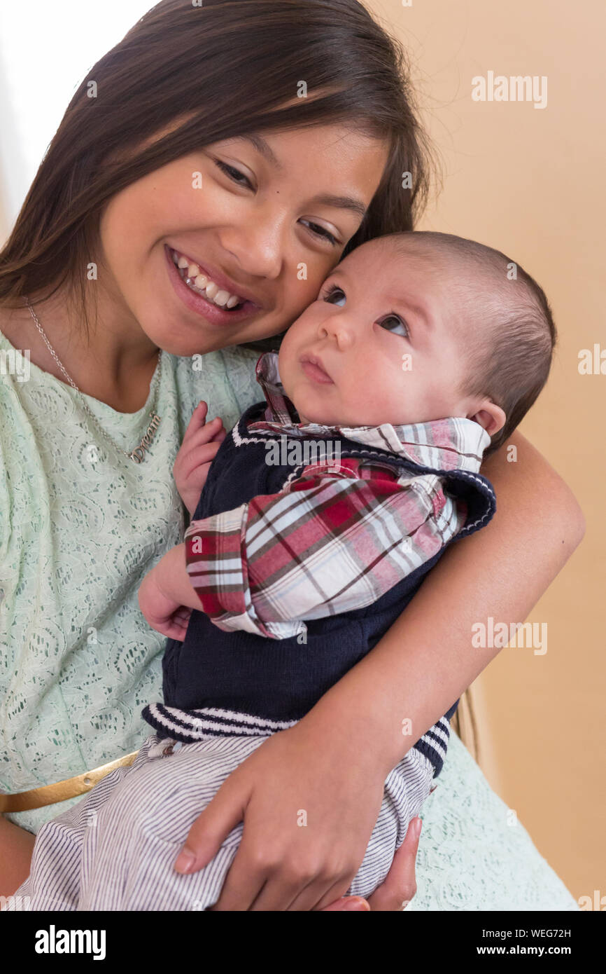 Asiatische Mädchen im Teenageralter Holding Baby gemischte Ethnie Bruder, San Jose, Kalifornien Stockfoto