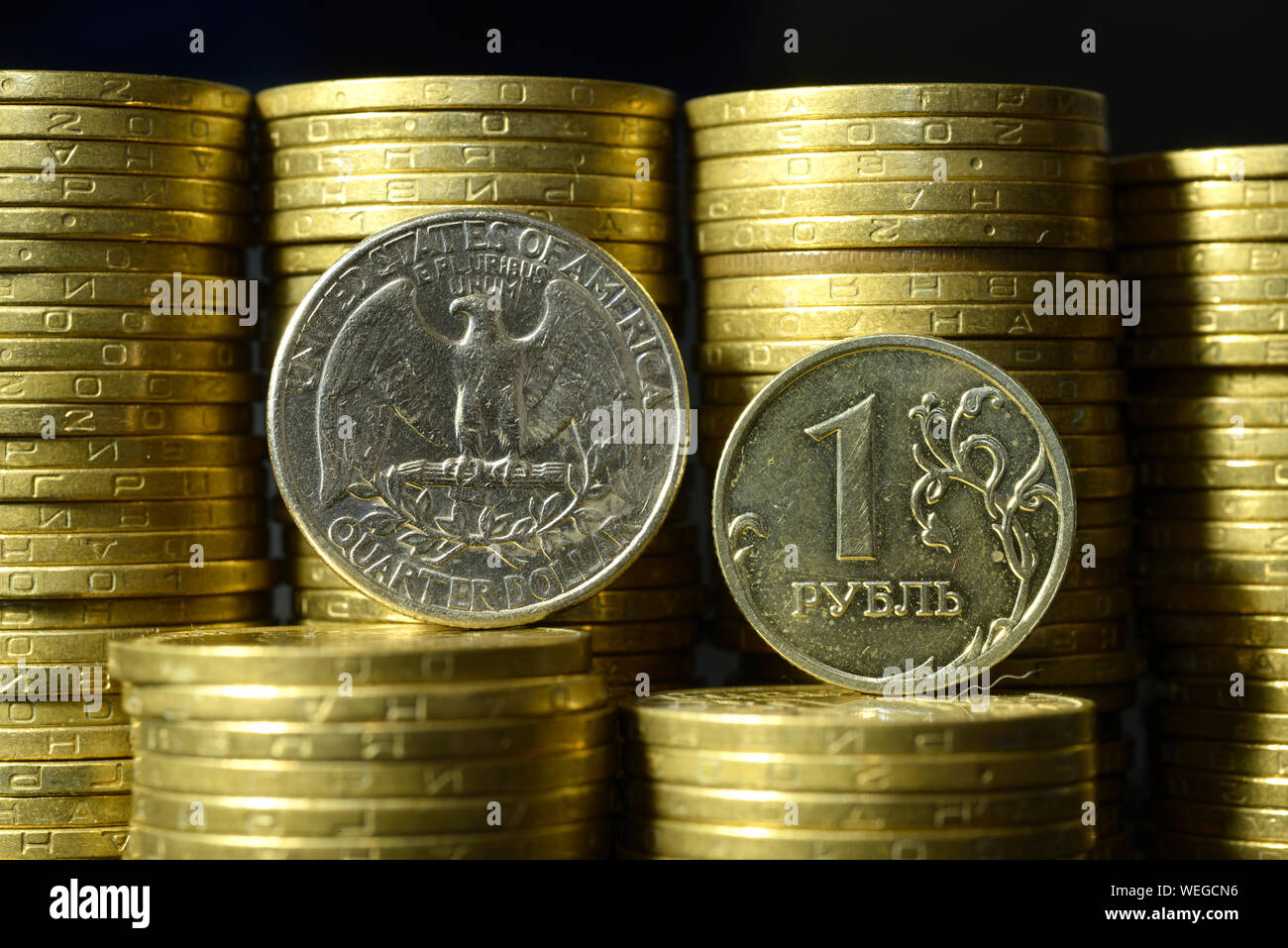 Quartal dollar Münze und einen Rubel Münze auf Kanten vor Stapel von Münzen platziert Stockfoto