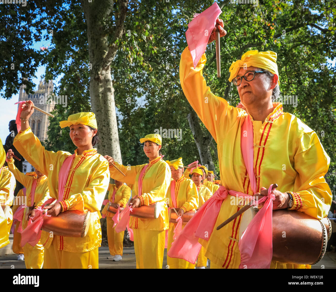 London, Großbritannien. August 2019. Eine Gruppe von Hüfttrommlern in hellen Kostümen üben ihre Routine. Praktizierende der chinesischen Falun Gong (auch bekannt als Falun Dafa) spirituellen Bewegung füllen den Parlamentsplatz und die umliegenden Gebiete und nehmen an einer Massenübung ihrer Fähigkeiten Teil. Die Teilnehmer kommen aus ganz Europa vor einer morgigen Konferenz in London. Kredit: Imageplotter/Alamy Live Nachrichten Stockfoto