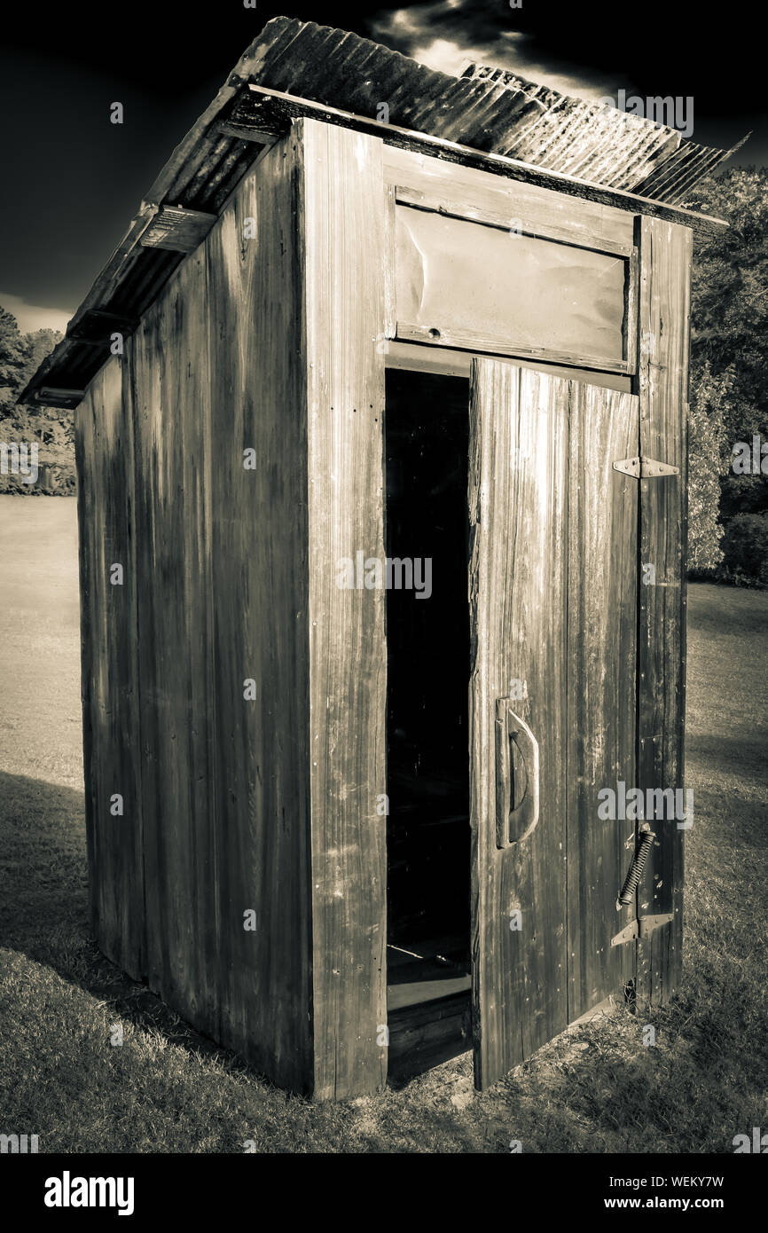 Alte, Verwitterte heraus - Haus oder Toilette, mit Tür offen mit rostigen Dach auf einem Hügel mit Bäumen im Südosten der USA Stockfoto