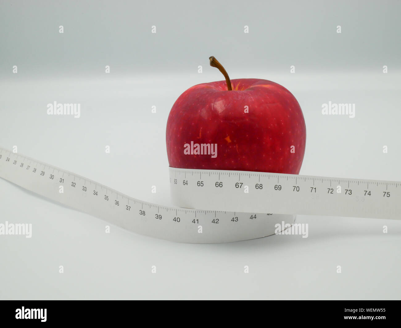 Red Apple und Maßband Zentimeter, die darstellen, Gewicht oder Diät Nahrung und Bewegung für Körper gut in Form Design Konzept isoliert auf weiß zurück reduzieren Stockfoto