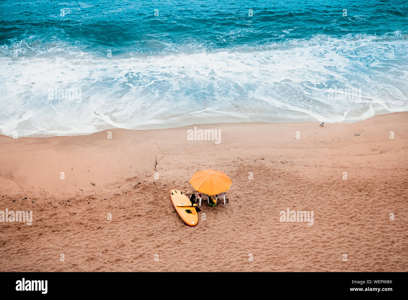 Sonnenschirm und Surfboard auf dem Sand des Strandes Stockfoto