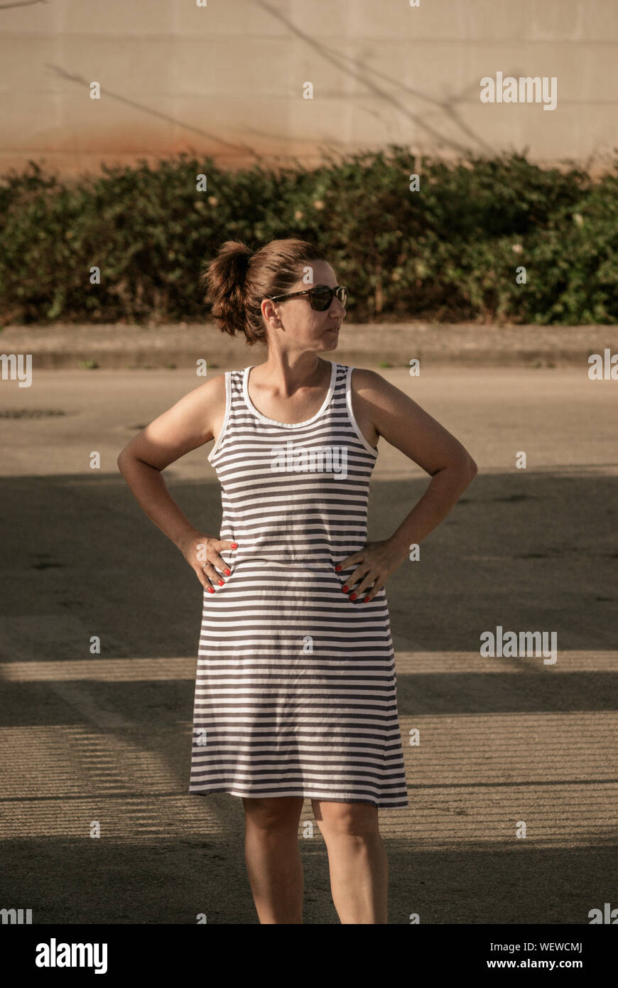 Reife Frau mit Hände auf Hüfte bei Feld während der sonnigen Tag Stockfoto