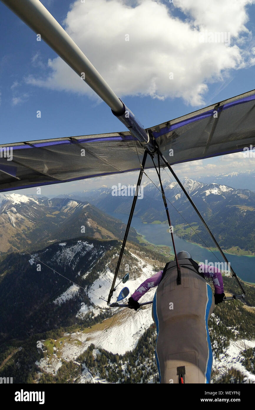 Hängegleiter Pilot fliegt über Berge mit Schnee, Gipfel und blauen Seen in den Tälern bedeckt. Extreme Sport in Greifenburg, Österreich Stockfoto